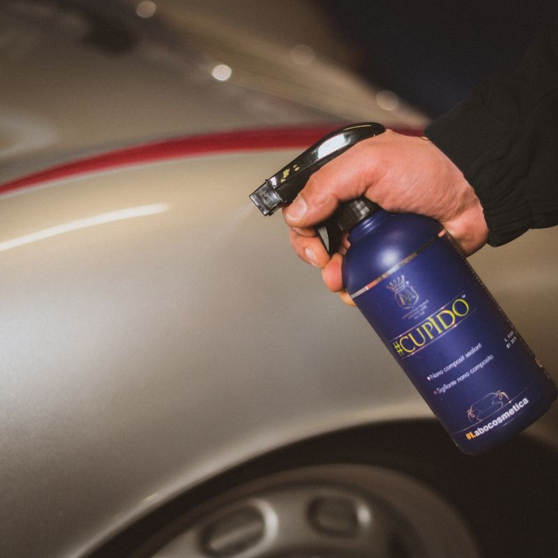 A detailer applying Labocosmetica Cupido spray on wipe off sealant to a car's paintwork.