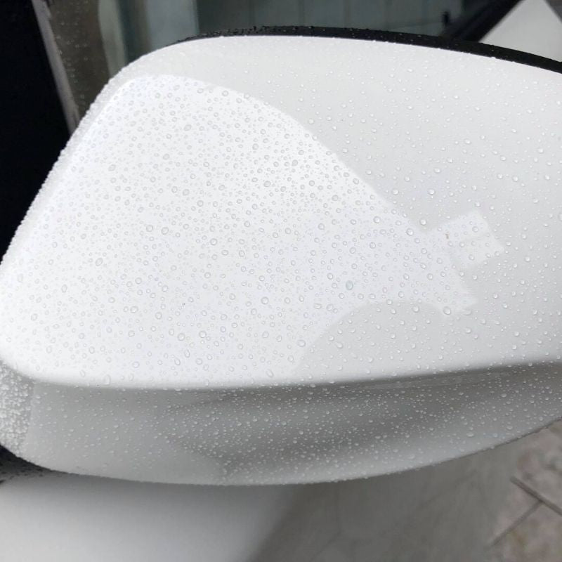 Close-up of water beading off a car wing mirror protected by Cupido ceramic spray.