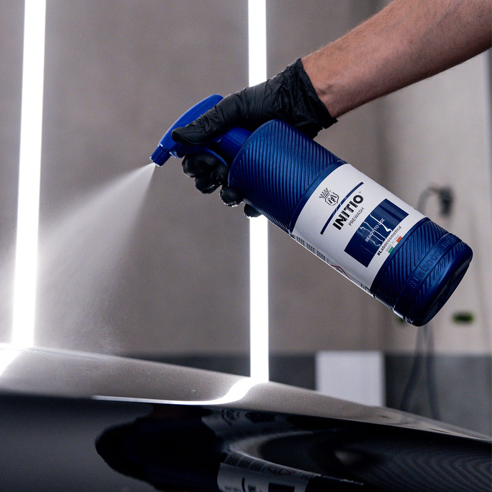 Person using a blue spray bottle labeled 'INITIOI' on a painted surface.